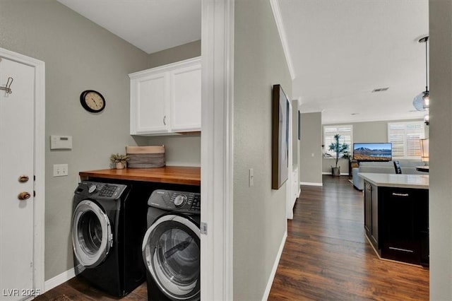 laundry room featuring washing machine and clothes dryer, cabinet space, dark wood-type flooring, and baseboards