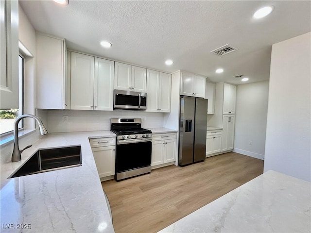 9552 Gold Bank Dr, Las Vegas, NV 89134 - kitchen featuring appliances with stainless steel finishes, light stone countertops, recessed lighting, light wood-style floors, and white cabinetry