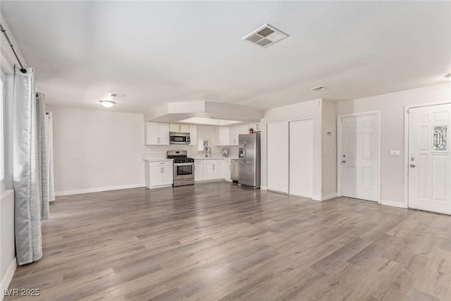 unfurnished living room featuring wood finished floors, baseboards, and a sink