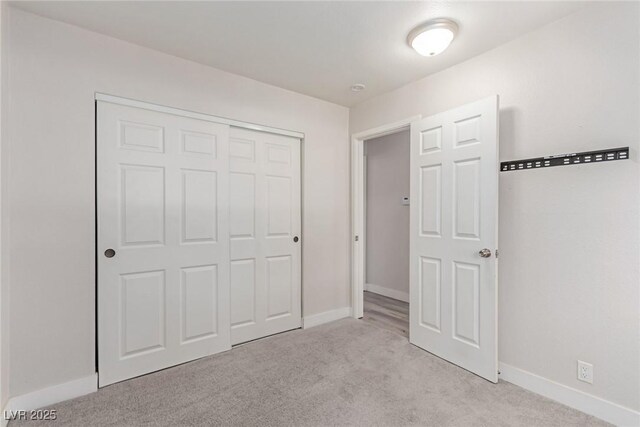 unfurnished bedroom with light colored carpet, baseboards, and a closet