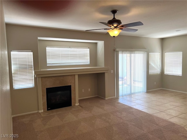 unfurnished living room featuring ceiling fan, a fireplace, tile patterned floors, carpet, and baseboards