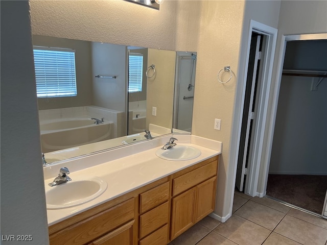 bathroom featuring tile patterned floors, a bath, double vanity, a shower stall, and a walk in closet