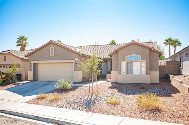 mediterranean / spanish-style home with a garage, concrete driveway, stucco siding, fence, and a tiled roof