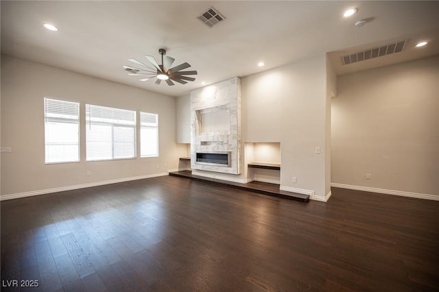 unfurnished living room featuring baseboards, ceiling fan, dark wood-style floors, a fireplace, and recessed lighting