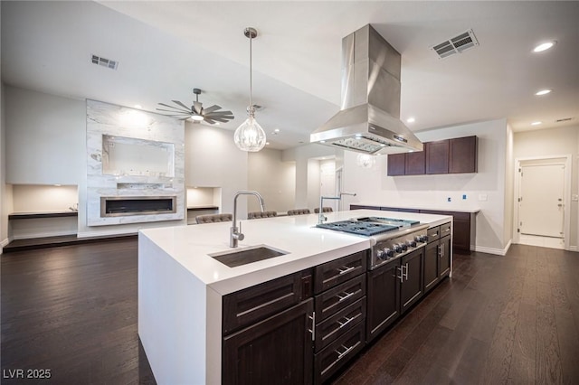 kitchen featuring a sink, stainless steel gas cooktop, island exhaust hood, dark wood-style floors, and a ceiling fan