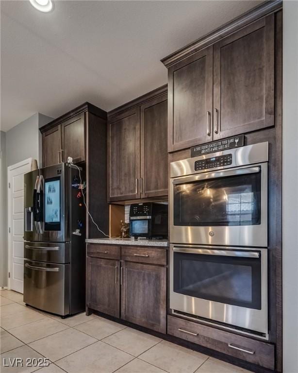 253 Kindly Way, Henderson, NV 89011 - kitchen with stainless steel appliances, light tile patterned floors, dark brown cabinets, and light stone counters