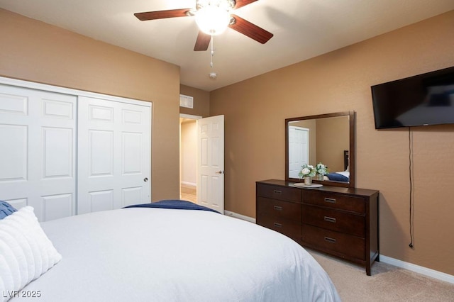 bedroom featuring a closet, light colored carpet, ceiling fan, and baseboards