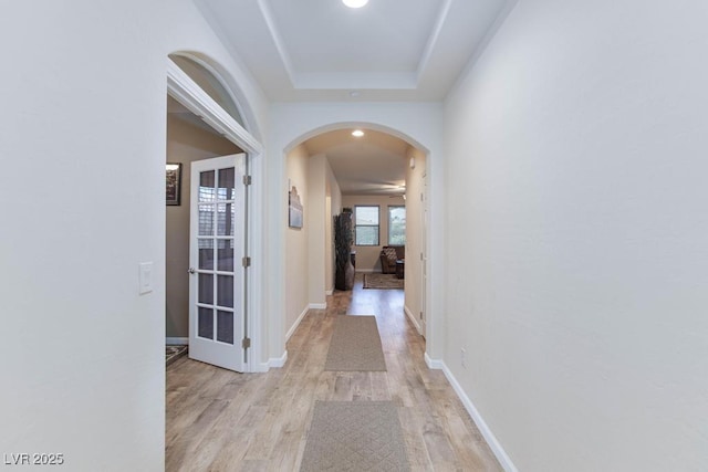 corridor with arched walkways, light wood-type flooring, baseboards, and recessed lighting
