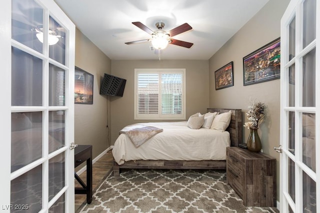 bedroom with french doors, a ceiling fan, baseboards, and wood finished floors