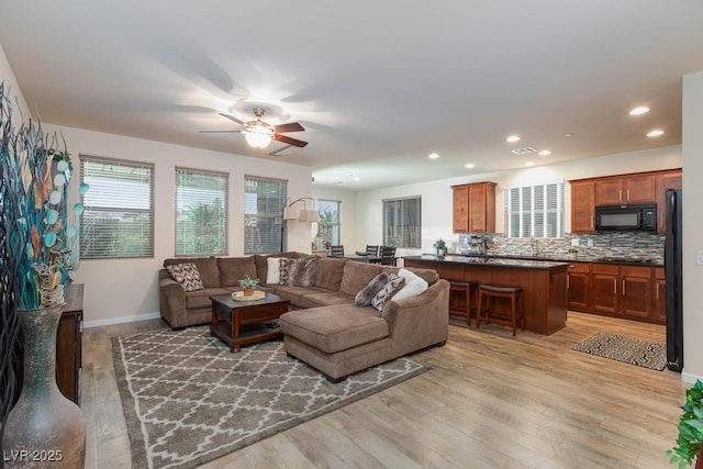 living room featuring light wood-type flooring, ceiling fan, recessed lighting, and baseboards