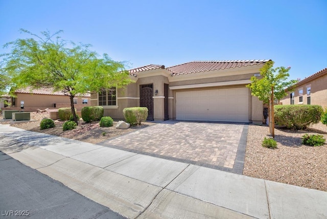 mediterranean / spanish-style home with an attached garage, a tile roof, stucco siding, and driveway