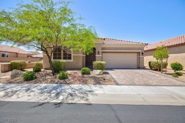 view of front of property featuring stucco siding, an attached garage, a tile roof, and driveway