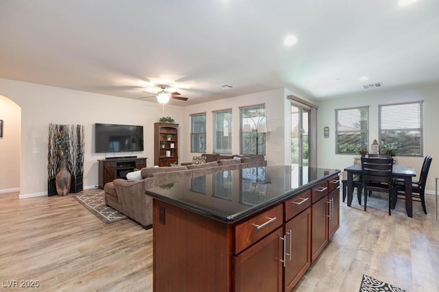 kitchen with ceiling fan, light wood finished floors, arched walkways, healthy amount of natural light, and recessed lighting