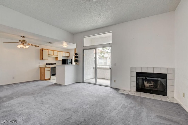 unfurnished living room featuring light colored carpet, a tile fireplace, ceiling fan, and a textured ceiling