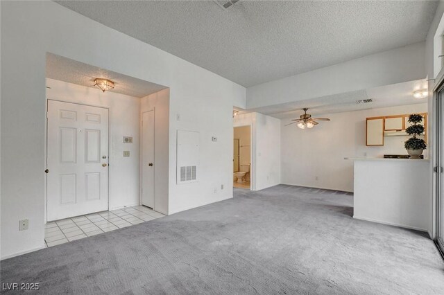 unfurnished living room with carpet floors, a ceiling fan, a textured ceiling, and tile patterned floors