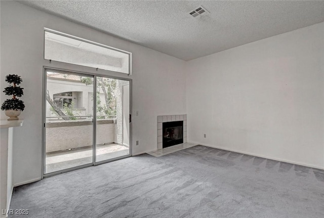unfurnished living room with carpet floors, a textured ceiling, and a fireplace
