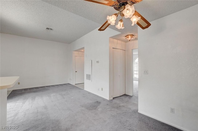 empty room with a ceiling fan, light carpet, a textured ceiling, and baseboards