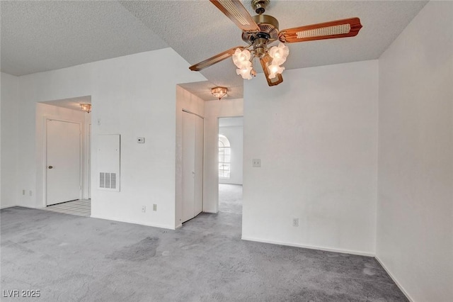 carpeted empty room with a ceiling fan, baseboards, and a textured ceiling