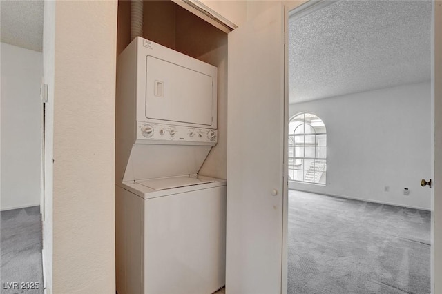 clothes washing area with carpet floors, estacked washer and dryer, and a textured ceiling