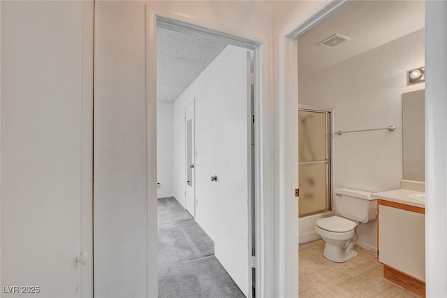 full bath featuring toilet, vanity, bath / shower combo with glass door, and a textured ceiling