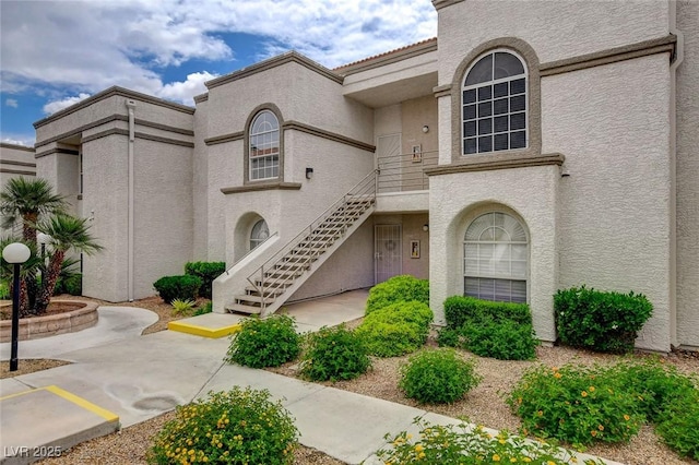 view of property with stairs and uncovered parking