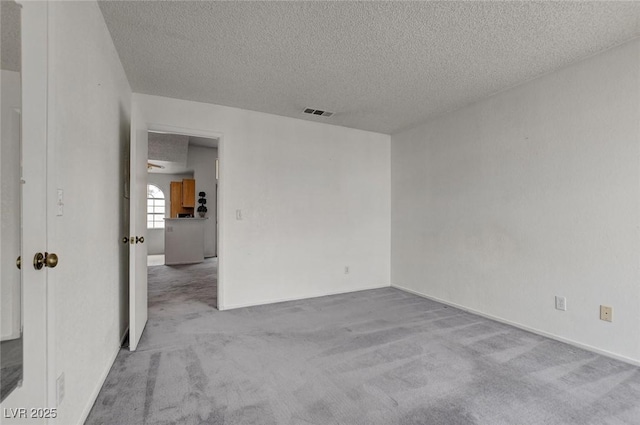 spare room featuring carpet flooring and a textured ceiling