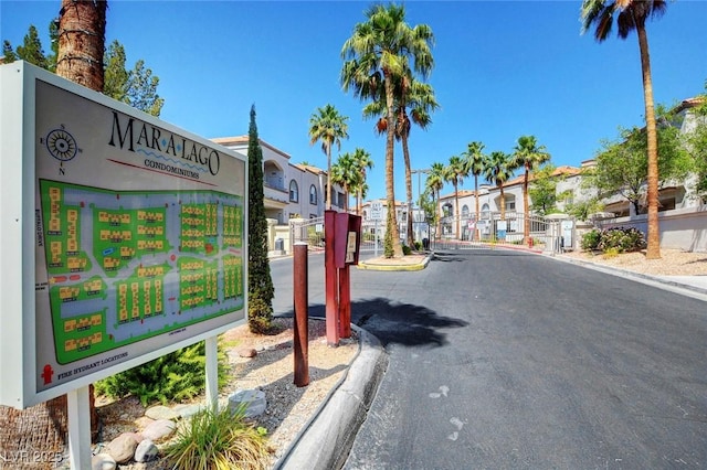 view of asphalt street with curbs and a gated entry