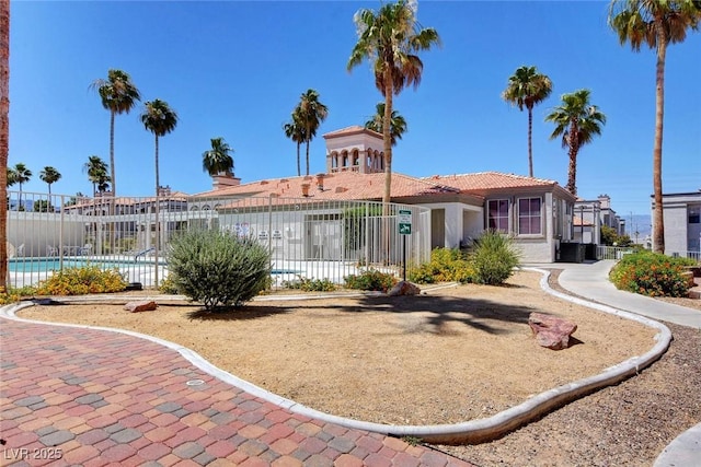 back of property with fence, stucco siding, a community pool, and cooling unit