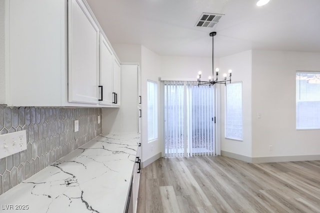 7849 Montour Falls St, Las Vegas, NV 89149 - kitchen with a chandelier, white cabinetry, tasteful backsplash, light stone countertops, and light wood-type flooring