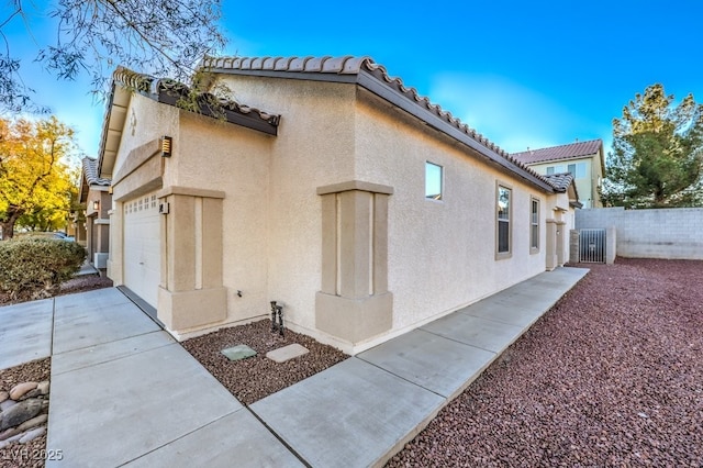 7849 Montour Falls St, Las Vegas, NV 89149 - view of side of home with stucco siding, fence, a garage, and a tiled roof