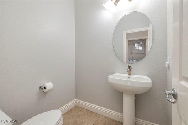 bathroom featuring toilet, baseboards, and tile patterned flooring