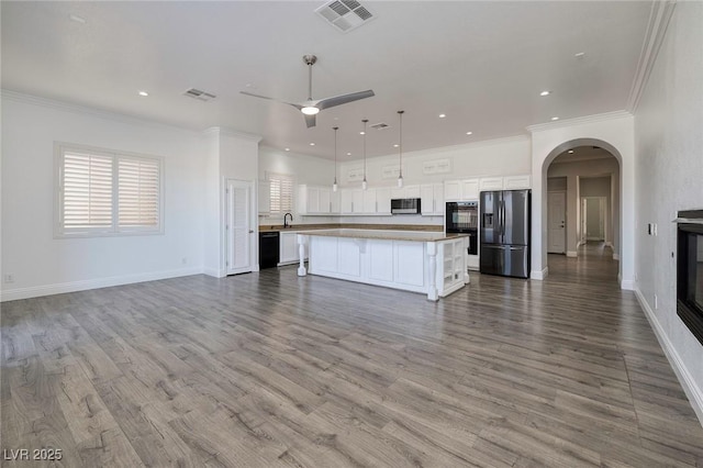 kitchen with black appliances, open floor plan, arched walkways, white cabinetry, and ceiling fan