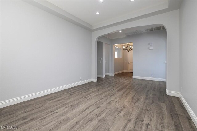 unfurnished room with arched walkways, a chandelier, wood finished floors, baseboards, and recessed lighting