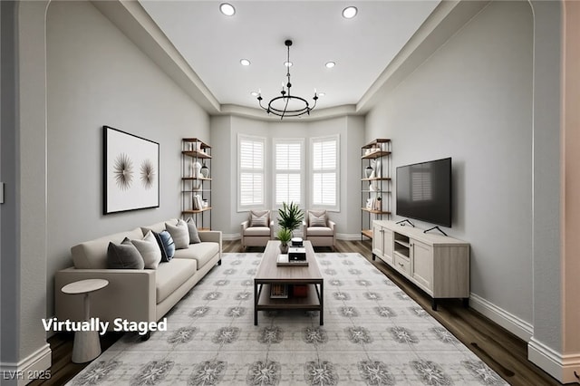 living area featuring a chandelier, recessed lighting, dark wood-style flooring, baseboards, and a tray ceiling