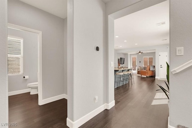 hallway featuring dark wood-type flooring, baseboards, and recessed lighting