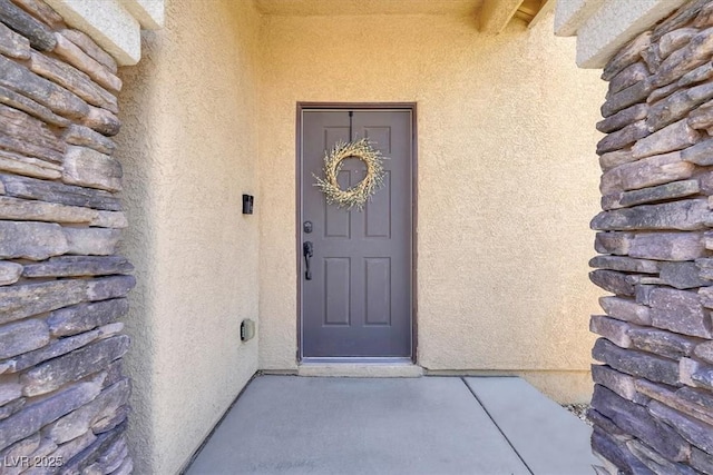 view of exterior entry with stucco siding and log siding