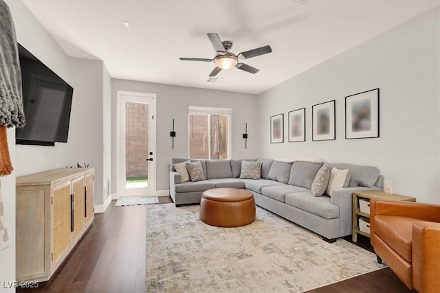 living area with dark wood finished floors, ceiling fan, and baseboards