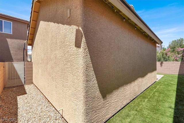 view of side of home with stucco siding and a fenced backyard