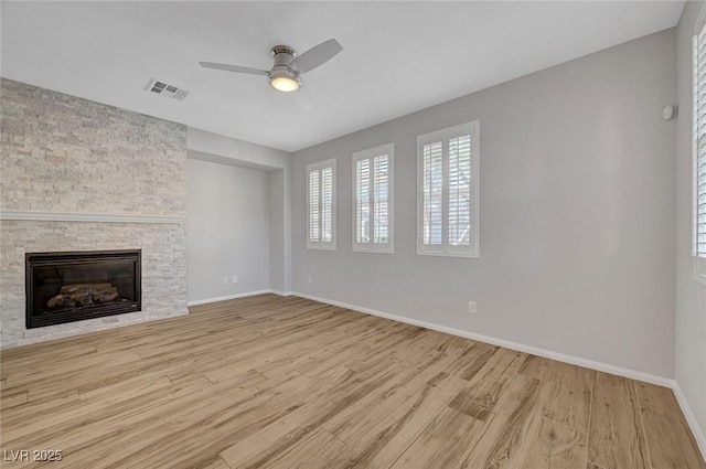 unfurnished living room featuring wood finished floors, baseboards, ceiling fan, and a fireplace