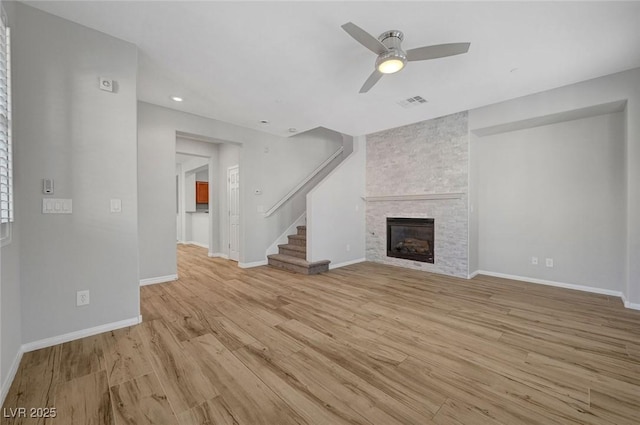 unfurnished living room featuring ceiling fan, light wood-type flooring, stairs, baseboards, and a fireplace