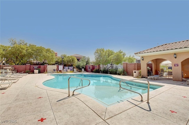 community pool with a patio area and fence