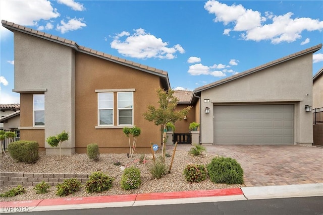 view of front of property with stucco siding, a garage, driveway, and a tile roof