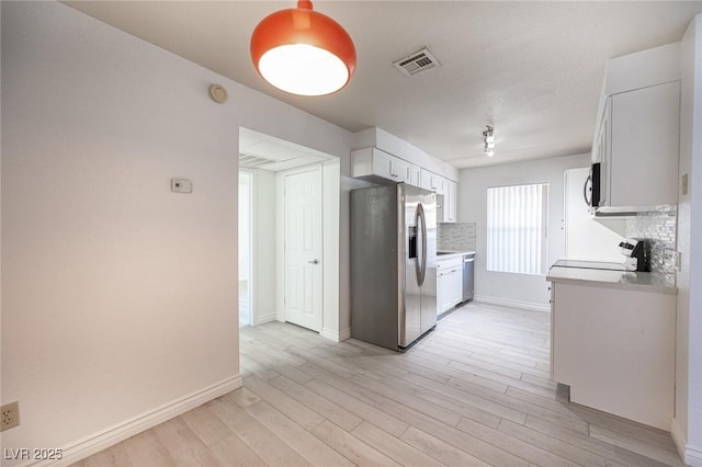 2606 S Durango Dr Unit 122, Las Vegas, NV 89117 - kitchen with stainless steel appliances, backsplash, light wood-style flooring, and white cabinetry