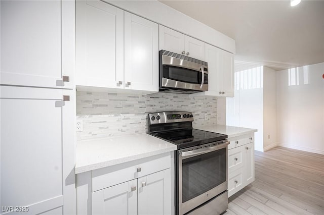 2606 S Durango Dr Unit 122, Las Vegas, NV 89117 - kitchen with stainless steel appliances, backsplash, white cabinetry, and light wood-style flooring