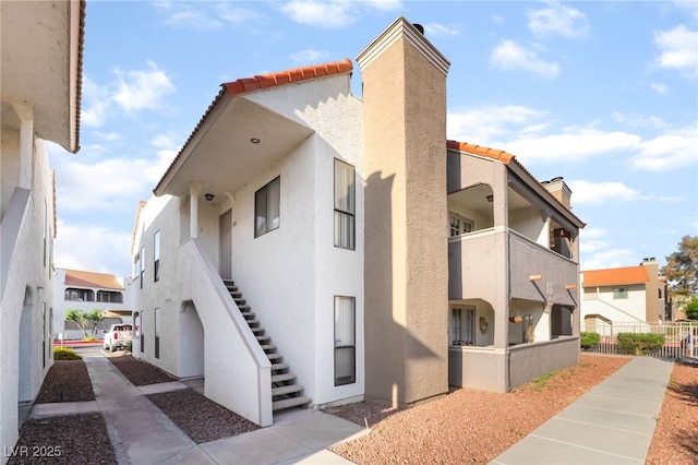 611 Bass Dr Unit C, Henderson, NV 89014 - view of side of property featuring a chimney, a tile roof, stucco siding, and stairway