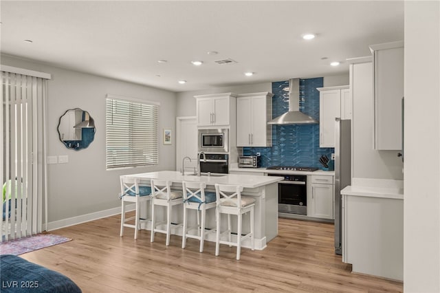5449 Hickory Tree St, Las Vegas, NV 89149 - kitchen with wall chimney exhaust hood, stainless steel appliances, a breakfast bar area, decorative backsplash, and a center island with sink