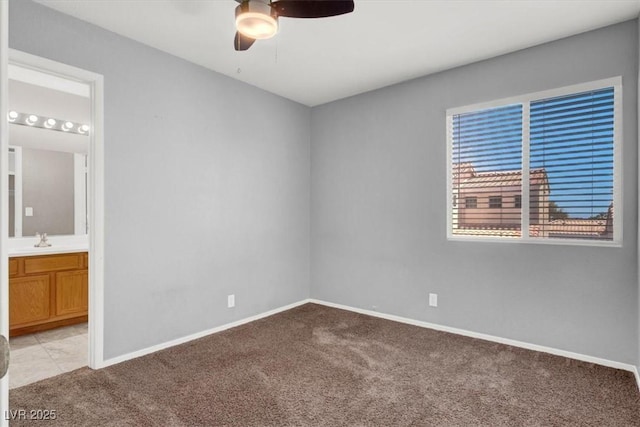 unfurnished bedroom featuring light colored carpet, a sink, ensuite bath, and baseboards