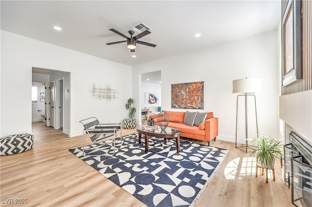 living room featuring light wood-style floors, a fireplace, recessed lighting, a ceiling fan, and baseboards