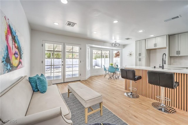 living room with recessed lighting, light wood-type flooring, french doors, and baseboards