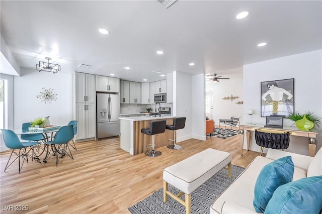 living area with light wood-type flooring, recessed lighting, baseboards, a chandelier, and ceiling fan